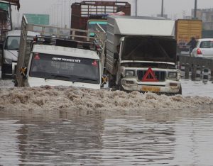 Gurgaon: Vehicle moves through a water logged road after heavy rains in Gurgaon on Saturday. PTI Photo 